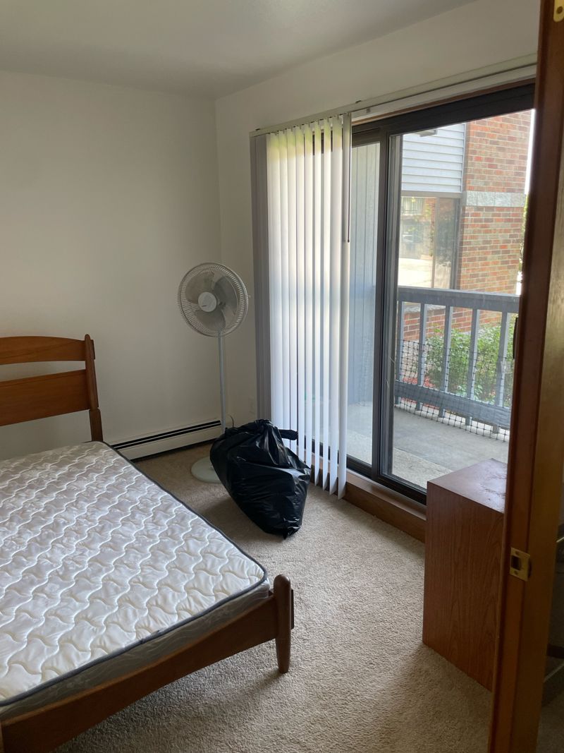 Bedroom with sliding glass door to the balcony and vertical blinds