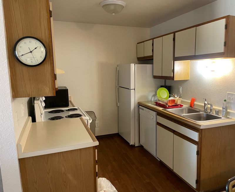 Kitchen with white appliances, dishwasher, double sink and wood cabinets